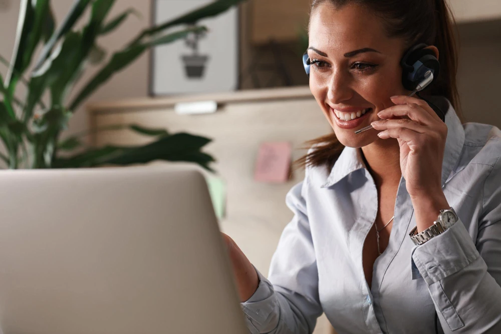 Remote customer support representative with a headset smiling during a client call